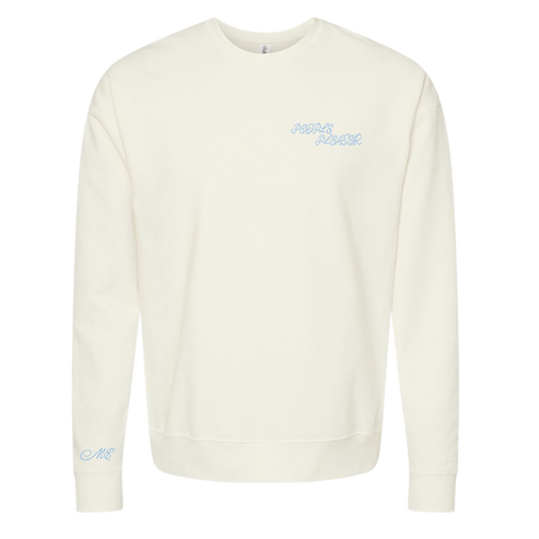An off-white crewneck sweatshirt with light blue cursive text on the left chest reading 'PEOPLE PLEASER' and a matching light blue monogram on the left sleeve